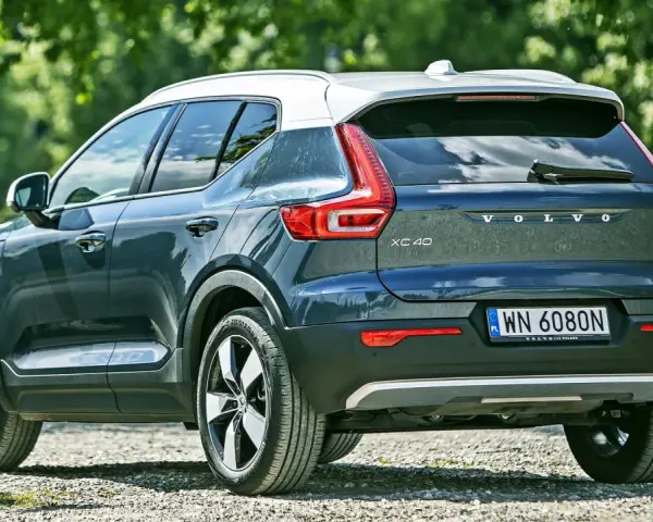 Tylna część ciemnoszarego Volvo XC40 z białym dachem, zaparkowanego na żwirowej drodze. Sprawdź aktualną volvo xc40 cena.