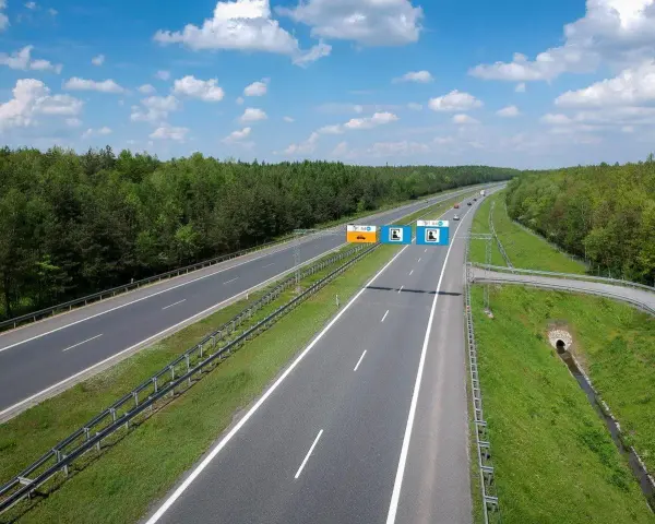 Znaki na autostradzie A4 informują, czy jest ona płatna. Widok na pustą autostradę w słoneczny dzień.