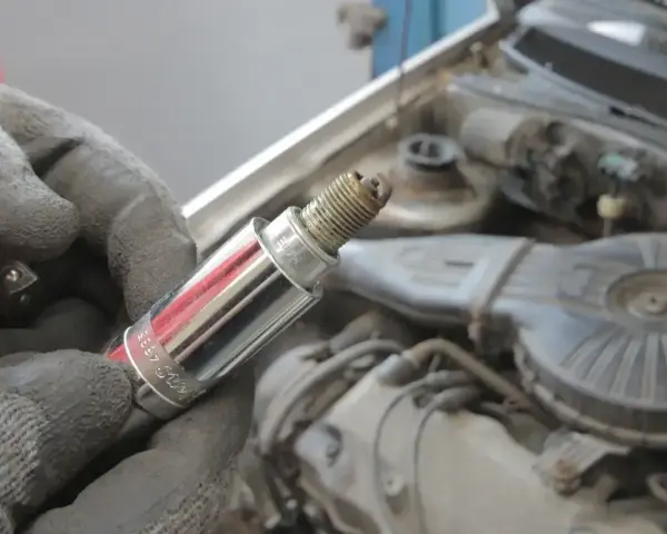 Rękawica trzyma świecę zapłonową, potencjalną przyczynę błędu dtc p0300 w Renault.