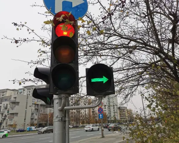 Sygnalizacja świetlna: czerwone światło na głównym słupku, a obok zielona strzałka warunkowa w prawo.