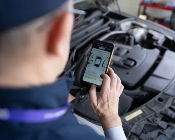 Mechanik sprawdza DTC BMW na smartfonie, analizując dane z silnika.