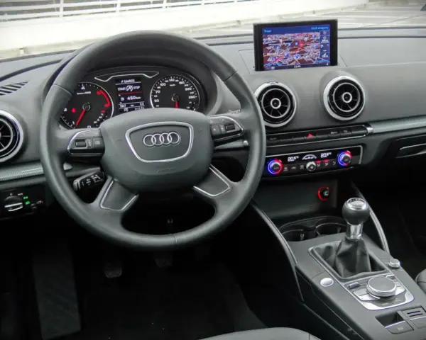 Wnętrze Audi A3 kombi: kierownica, nawigacja, panel klimatyzacji i skrzynia biegów.