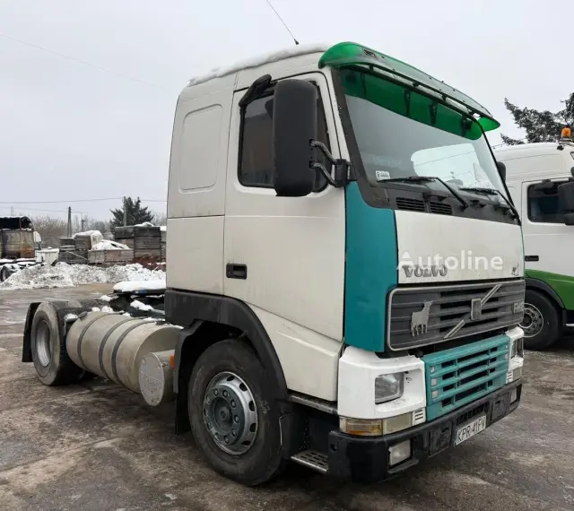 Ciężarówka Volvo FH12 z zielonym akcentem na kabinie, zaparkowana na zewnątrz w zimowy dzień.