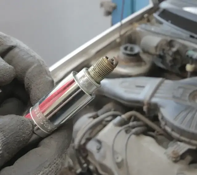 Rękawica trzyma świecę zapłonową, potencjalną przyczynę błędu dtc p0300 w Renault.