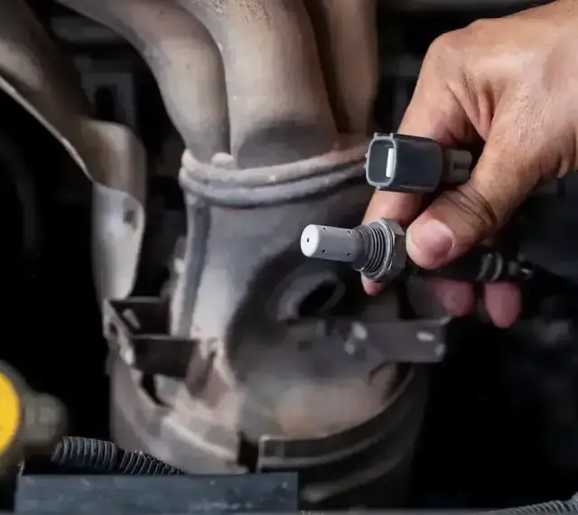Dłoń trzyma czujnik tlenu, potencjalna przyczyna błędu DTC P0420 w Volkswagenie.