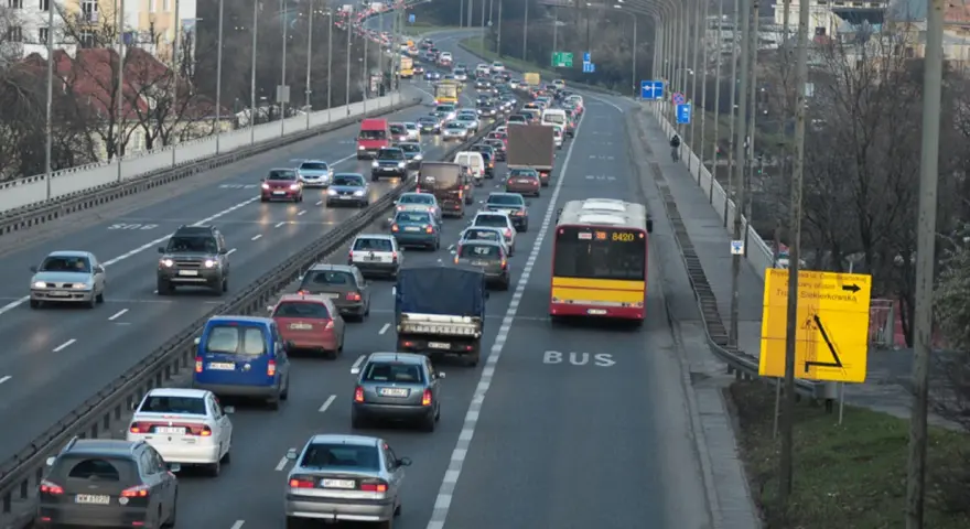 Autobus jedzie pasem dla autobusów. Wokół ruch samochodowy.
