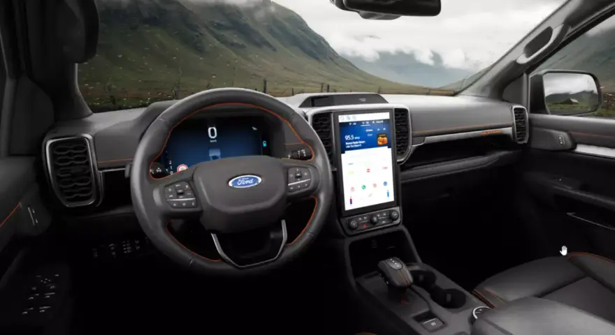 Wnętrze nowoczesnego Ford SUV z dużym ekranem dotykowym i cyfrowymi zegarami. Widok na górzysty krajobraz przez przednią szybę.