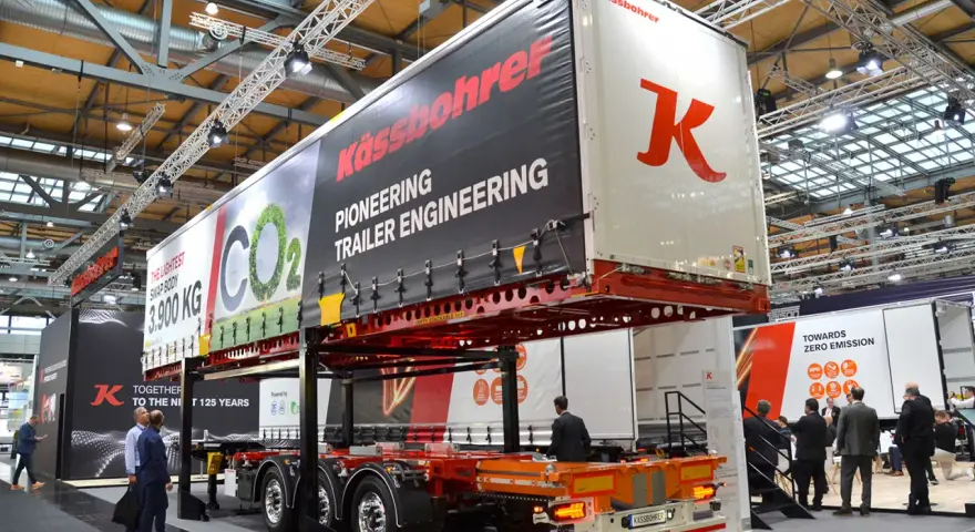 Nowa naczepa Kässbohrer z napisem "Pioneering Trailer Engineering". W tle ludzie zwiedzają targi.