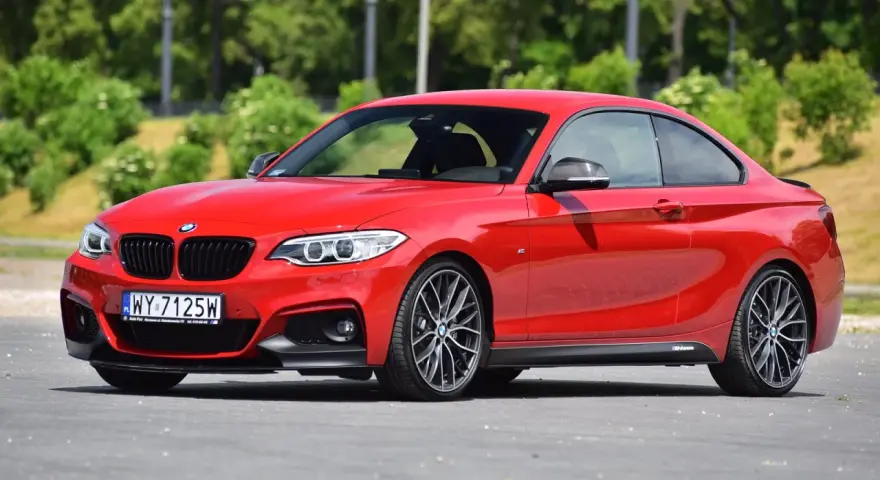 Czerwone BMW f23 coupe z czarnymi dodatkami i felgami stoi na asfalcie.