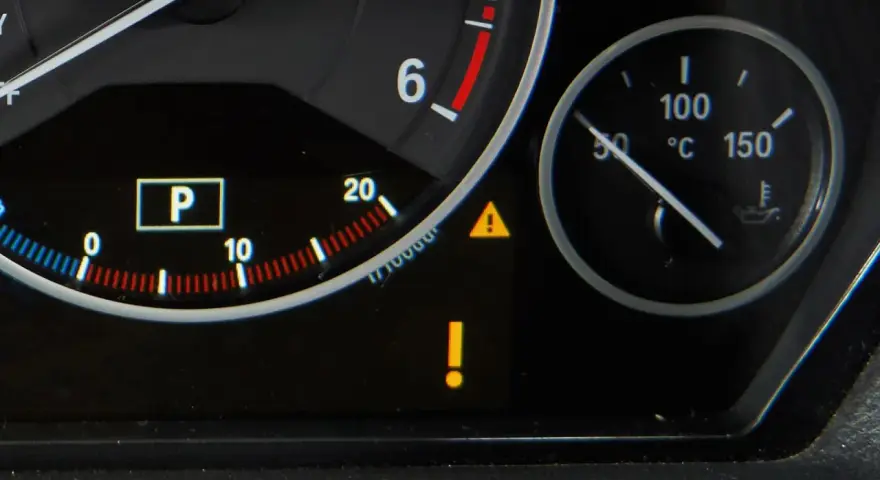 Na desce rozdzielczej świeci się kontrolka żółty wykrzyknik w trójkącie, sygnalizując problem. Obok wskaźnik temperatury oleju.
