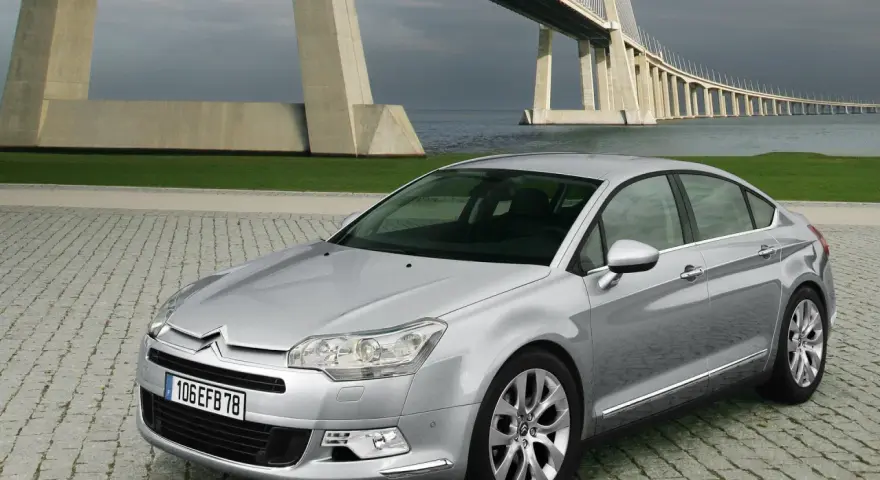 Srebrny Citroen C5 na tle mostu. Wiele osób chwali ten model, a opinie o Citroen C5 są zazwyczaj pozytywne.
