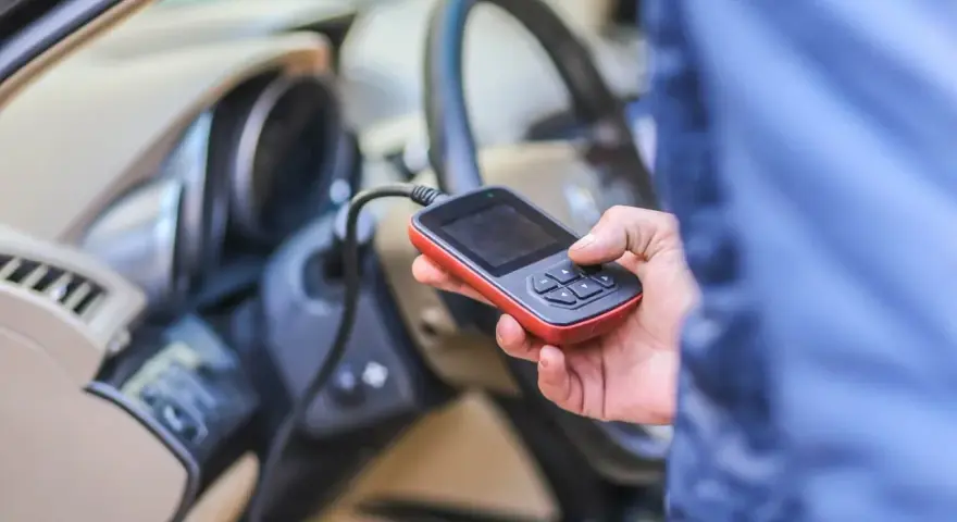 Diagnostyka Renault, być może błąd DTC B1267. Ręka trzyma urządzenie diagnostyczne podłączone do samochodu.