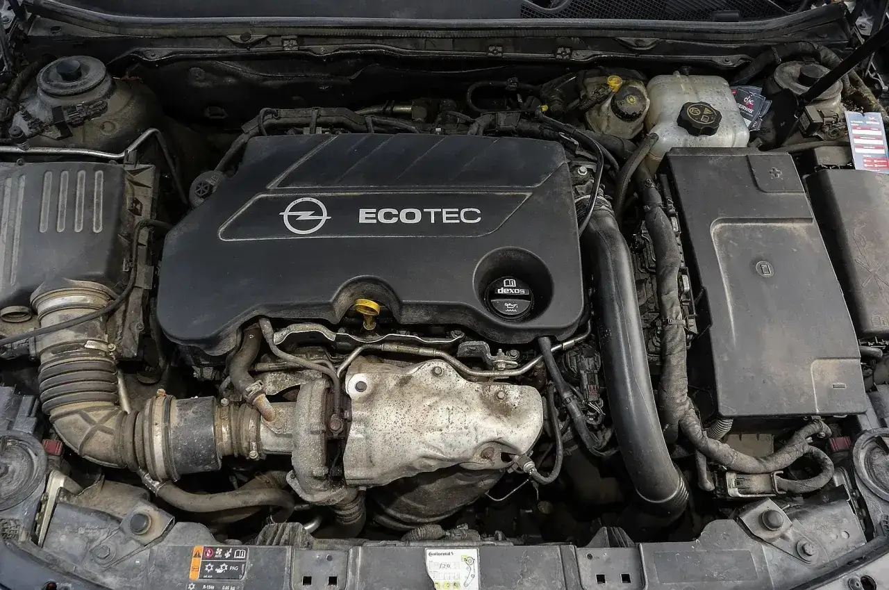 Silnik Opel Ecotec. Widoczne elementy układu dolotowego i turbosprężarki. Objawy uszkodzenia poduszki silnika mogą być różne, np. wibracje.