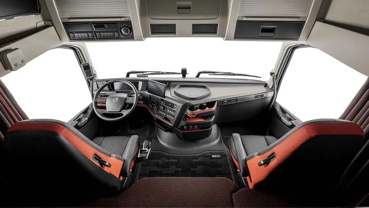 Wnętrze Volvo FH12 z dwoma fotelami, deską rozdzielczą i kierownicą.