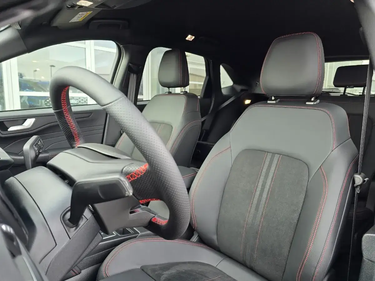 Wnętrze Ford SUV z czarnymi skórzanymi fotelami i czerwonymi przeszyciami. Kierownica sportowa z perforacją.