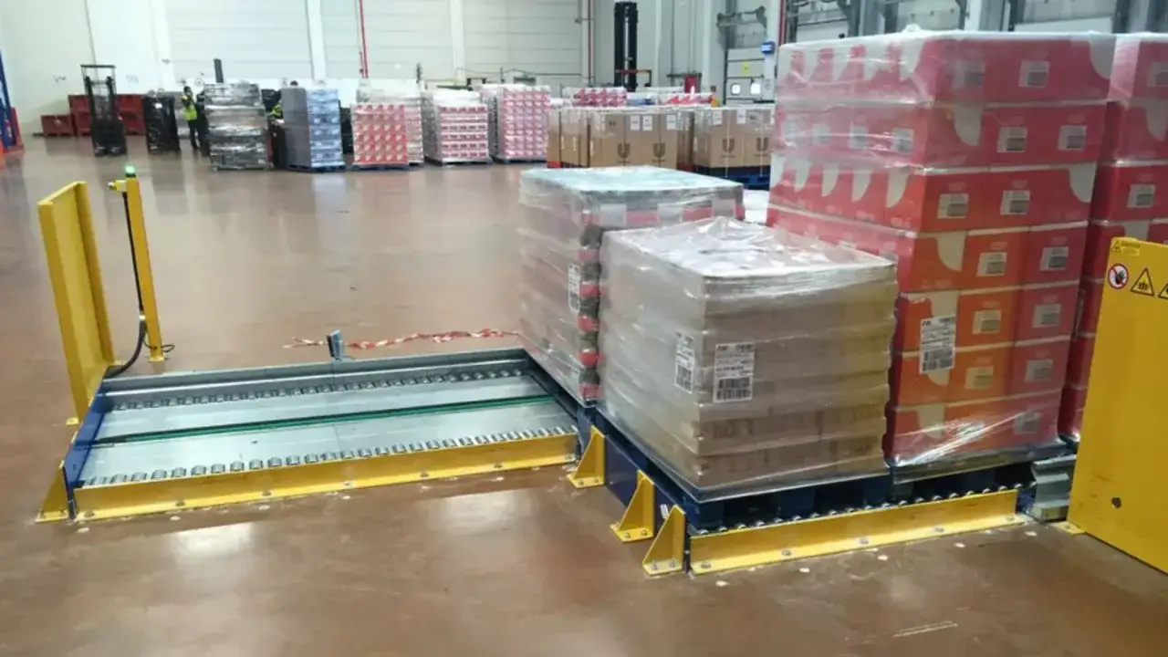 Magazyn z paletami towarów, systemem przenośników i żółtą osłoną. Efektywne rozwiązanie do cross docking.