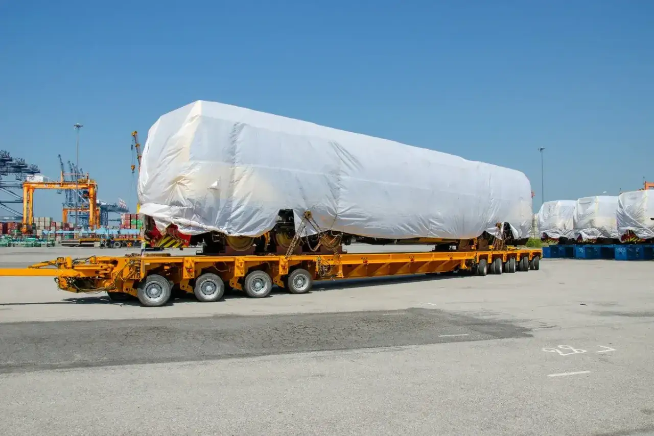 Ciężki ładunek, prawdopodobnie część pociągu, zabezpieczony do transportu zgodnie z warunkami CPT Incoterms.