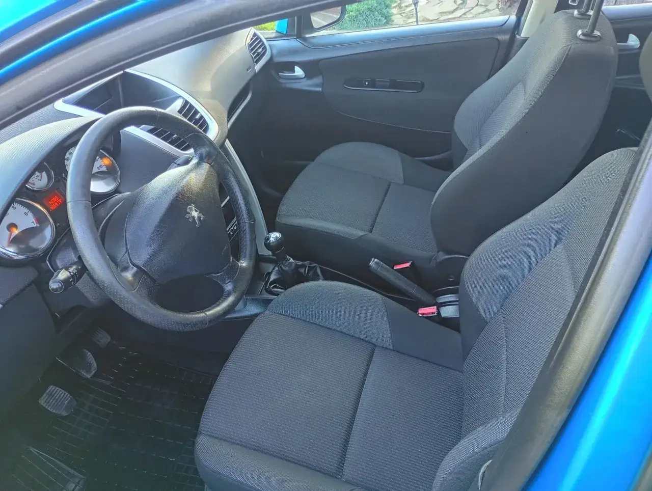 Wnętrze Peugeota 207 1.4 benzyna. Widoczne fotele, kierownica, deska rozdzielcza i dźwignia zmiany biegów.
