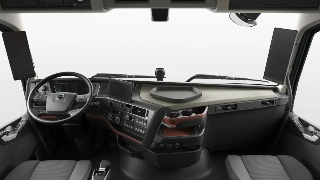 Wnętrze kabiny ciężarówki Volvo 750 z kierownicą, ekranem multimedialnym i wygodnymi siedzeniami.