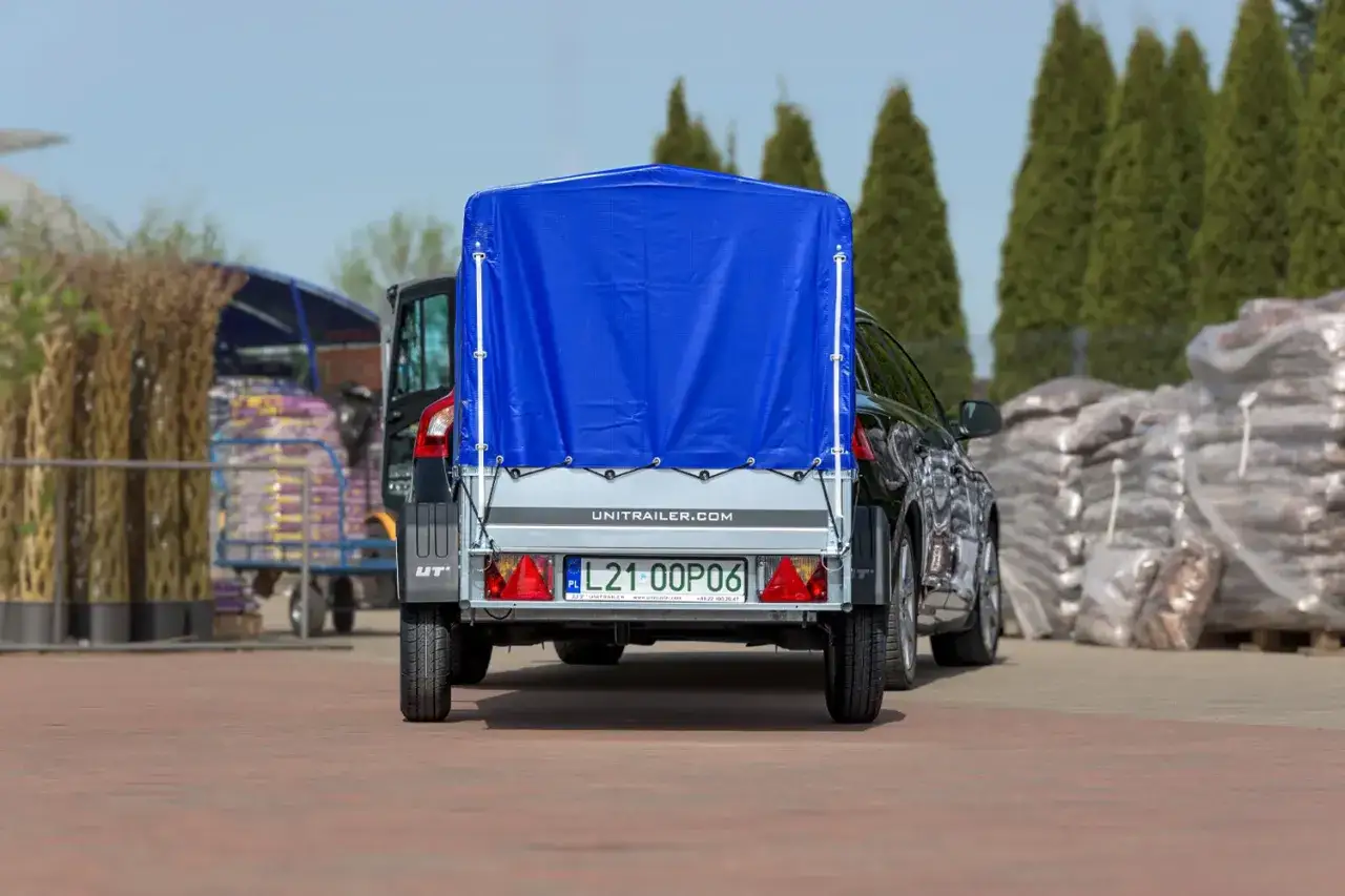 Nowa przyczepa lekka z niebieską plandeką gotowa do transportu.