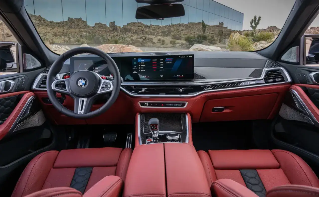 Wnętrze luksusowego x6 bmw z czerwonymi skórzanymi fotelami i nowoczesnym panelem sterowania.