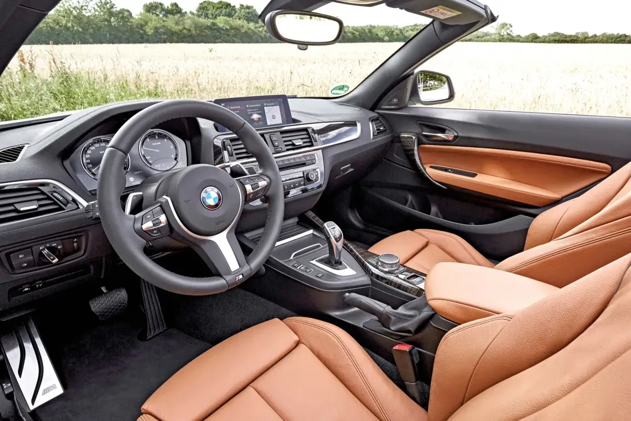 Wnętrze kabrioletu BMW f23 z brązową skórzaną tapicerką i widokiem na pole.