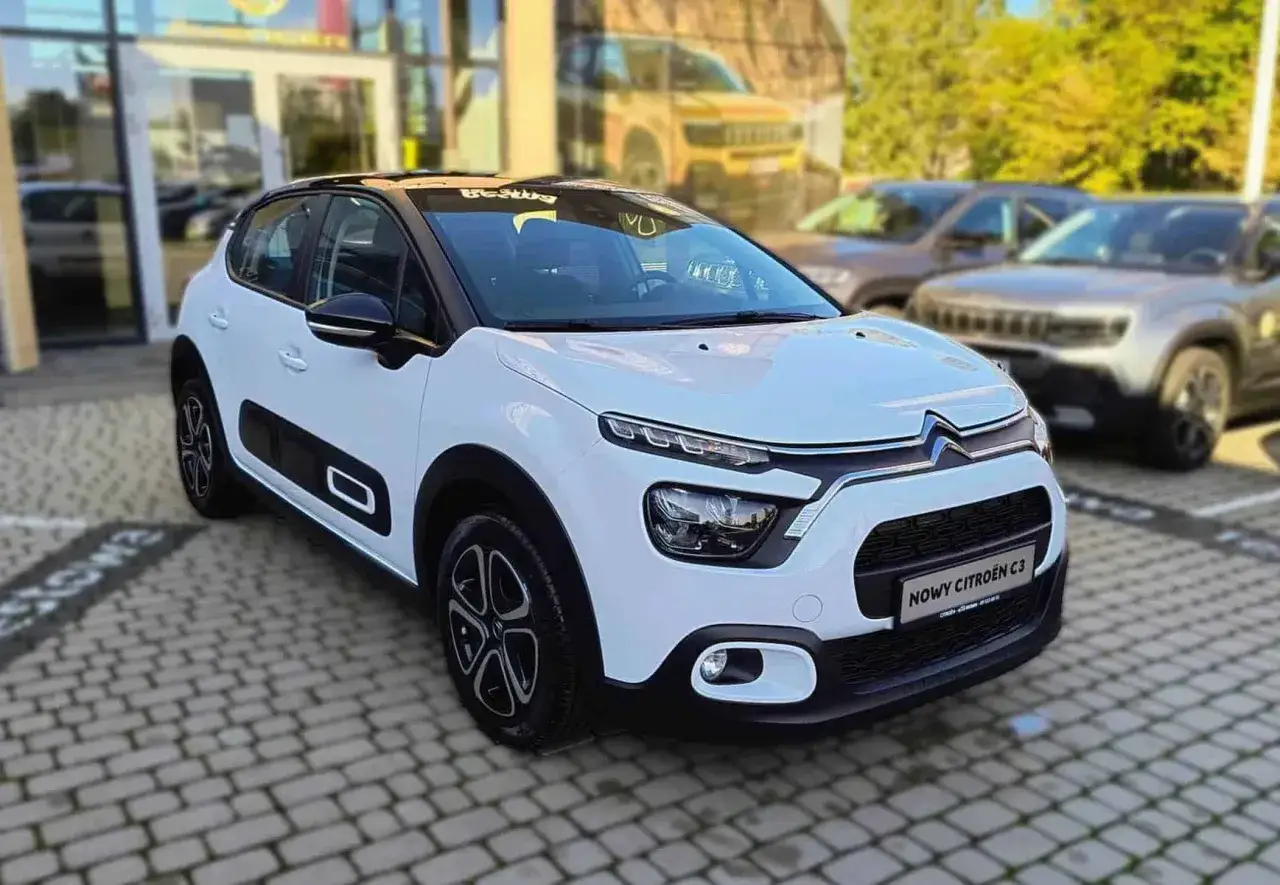 Biały Citroen C3 z czarnym dachem, zaparkowany przed salonem. Sprawdź atrakcyjną citroen c3 cena!