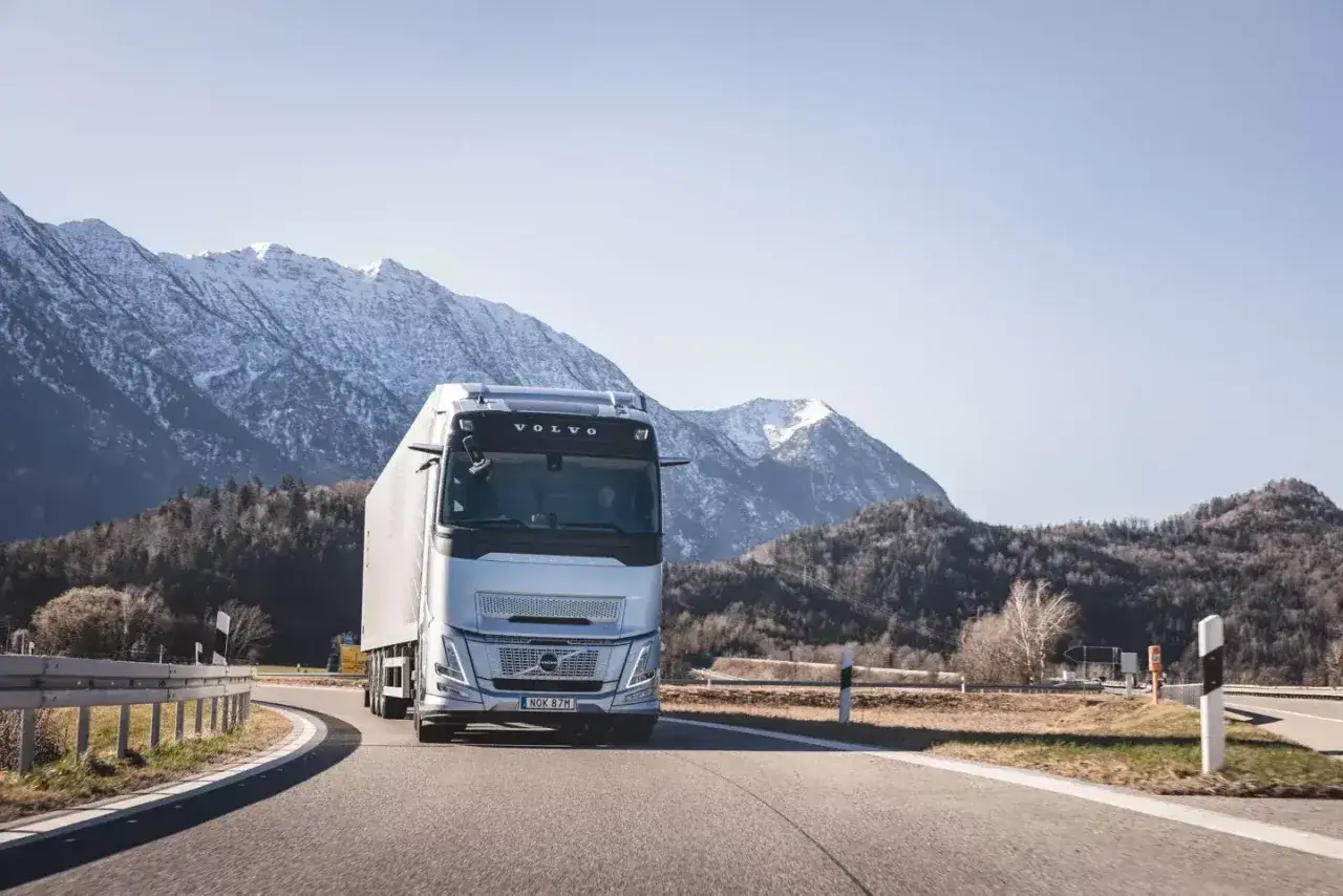 Srebrny Volvo FH13 z naczepą pokonuje górską trasę.