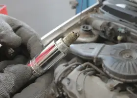 Rękawica trzyma świecę zapłonową, potencjalną przyczynę błędu dtc p0300 w Renault.