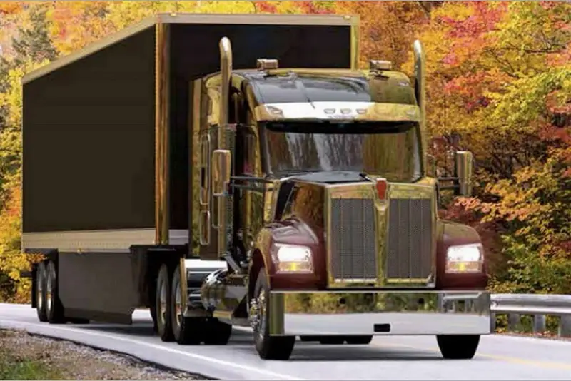 Błyszczący Kenworth W900 z przyczepą jedzie drogą wśród jesiennych drzew.