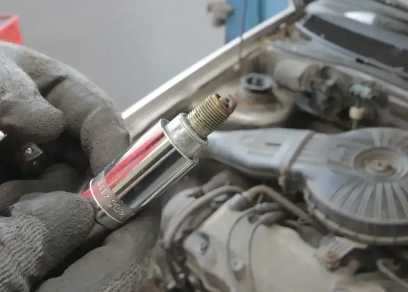 Rękawica trzyma świecę zapłonową, potencjalną przyczynę błędu dtc p0300 w Renault.