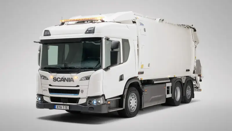 Biała śmieciarka Scania Streamline z niebieskim akcentem na grillu i pomarańczowymi światłami ostrzegawczymi na dachu.